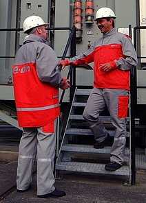 Zwei Mitarbeiter von EON in Schutzkleidung im Gespräch.