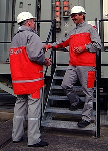 Zwei Mitarbeiter von EON in Schutzkleidung im Gespräch.