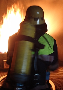 Feuerwehrmänner mit Atemmasken dringen zum Brandherd vor.
