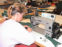 Eine Mitarbeiterin arbeitet an einer Nähmaschine.