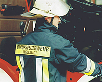Ein Feuerwehrmann trägt die Einsatzjacke Bayern.