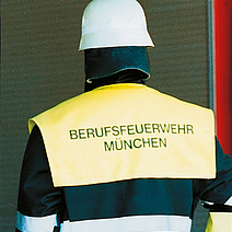 Ein Feuerwehrmann mit Helm trägt die Einsatzjacke München